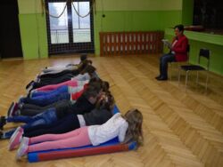 Dzieci słuchają głośnego czytania fragmentów lektury pt. "Dzieci z Bullerbyn" o zabawach na śniegu