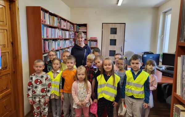 Dzieci biorące udział w lekcji bibliotecznej na wspólnym zdjęciu z bibliotekarką