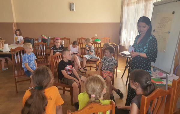 Bibliotekarz wraz z dziećmi podczas rozwiazywania krzyżówki