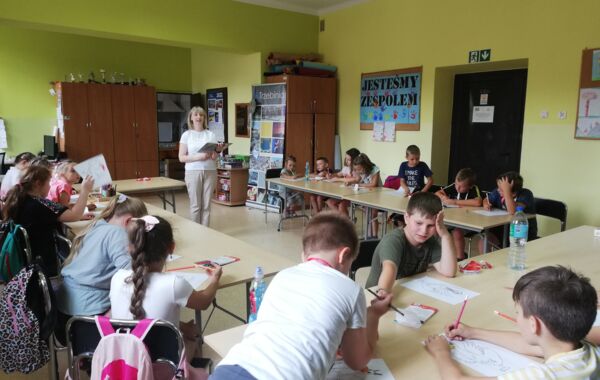 Dzieci podczas słuchania czytanej przez bibliotekarza książki