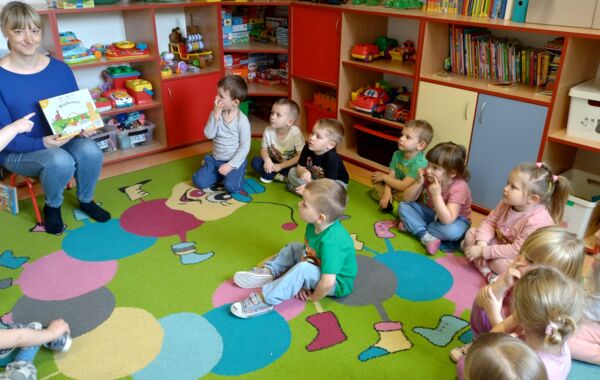 Bibliotekarka prezentuje dzieciom jedną z czytanych książeczek