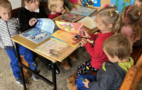 Dzieci siedzące przy stoliku. W tle – gazetka jesienna
