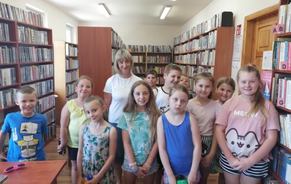 Zdjęcie grupowe dzieci biorących udział w lekcji bibliotecznej wraz z bibliotekarką