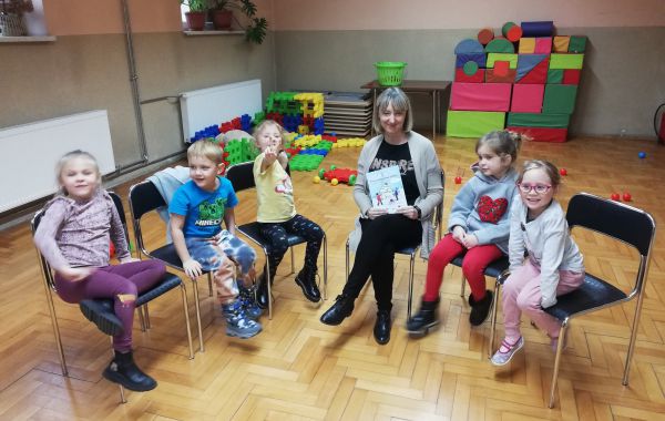 Bibliotekarz siedzący z dziećmi w półokręgu
