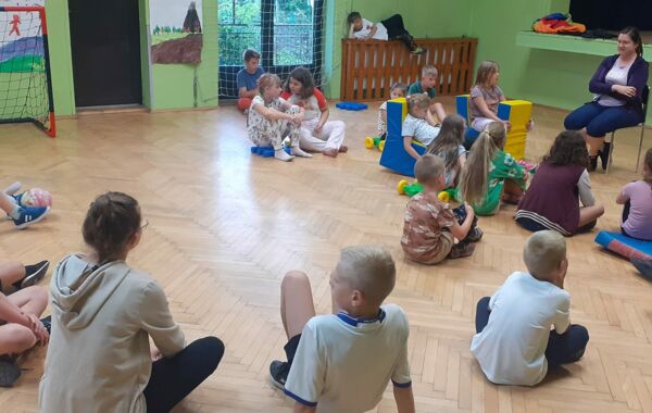 Dzieci podczas zajęć z bibliotekarką na Sali w domu kultury w Lgocie
