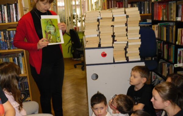 Bibliotekarz w trakcie prezentacji książki. W tle nowości