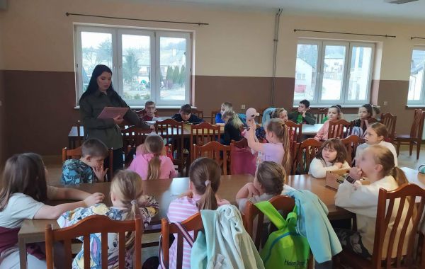 Bibliotekarz czytający dzieciom siedzącym przy stoliku