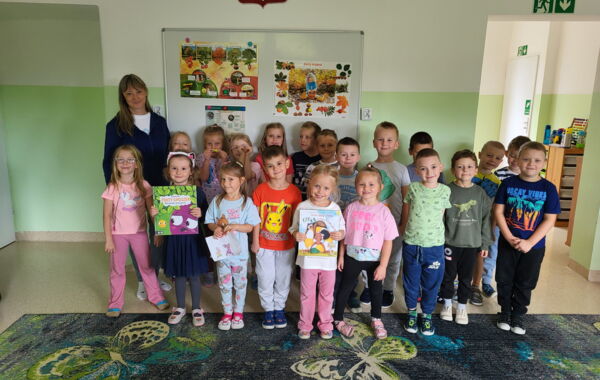 Bibliotekarka oraz dzieci biorące udział w lekcji bibliotecznej