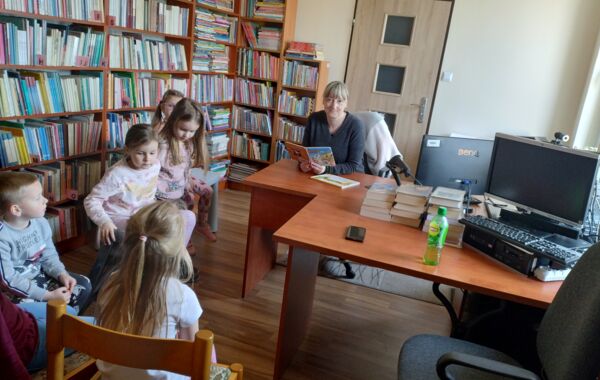 Bibliotekarka podczas czytania dzieciom książeczki