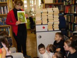 Bibliotekarz w trakcie prezentacji książki. W tle nowości