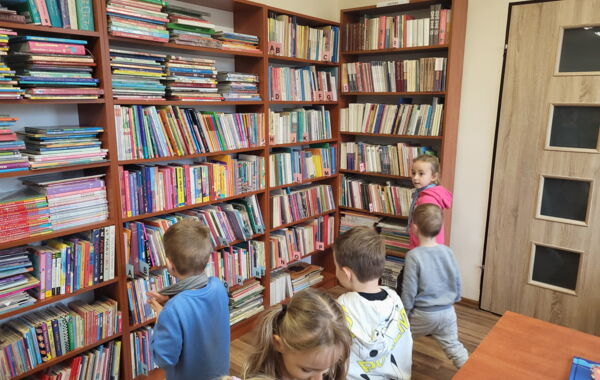 Przedzkolaki stojące przy regałach z książkami