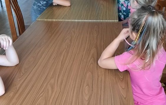 Uczestnicy spotkania w trakcie głośnego czytania. W tle bibliotekarz