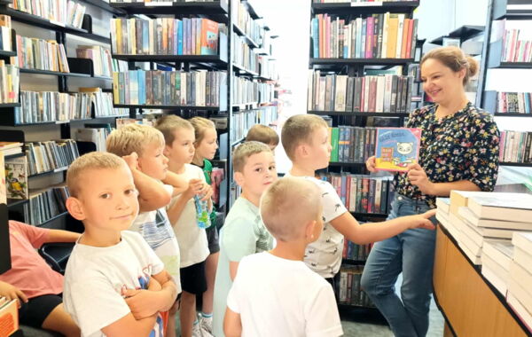 Dzieci stojace wokół regałów z książkami