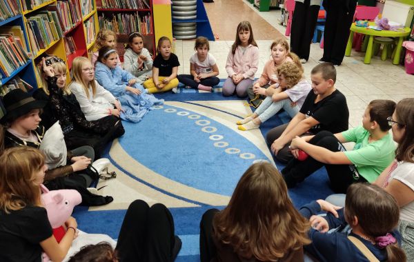 Uczestnicy Nocy w Bibliotece siedzący w kółku na dywanie