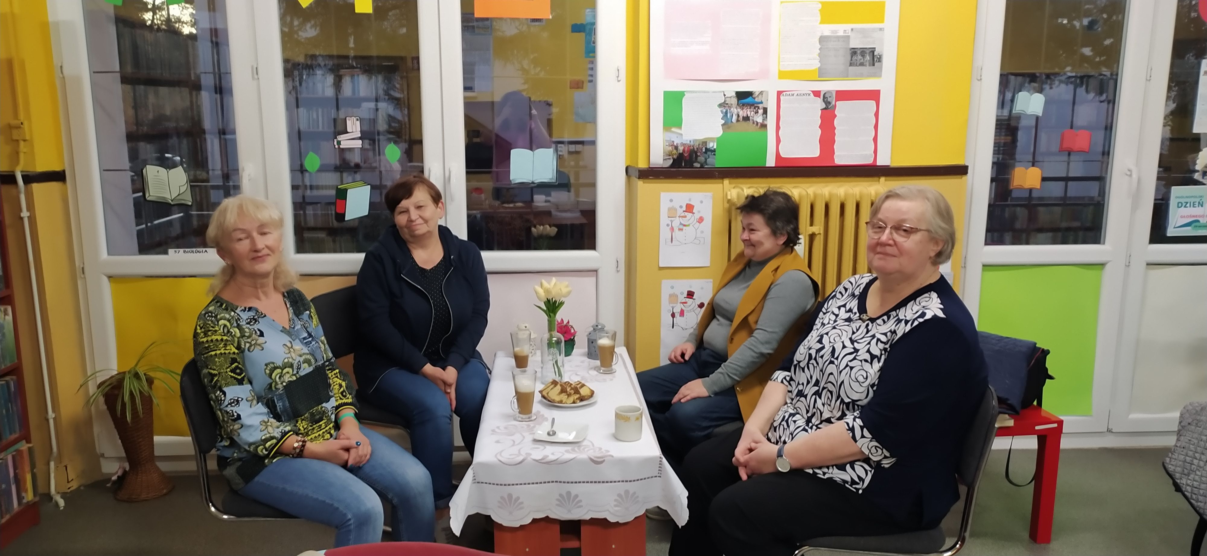 Uczestniczki spotkania siedzące przy stoliku z kawą i ciastkami
