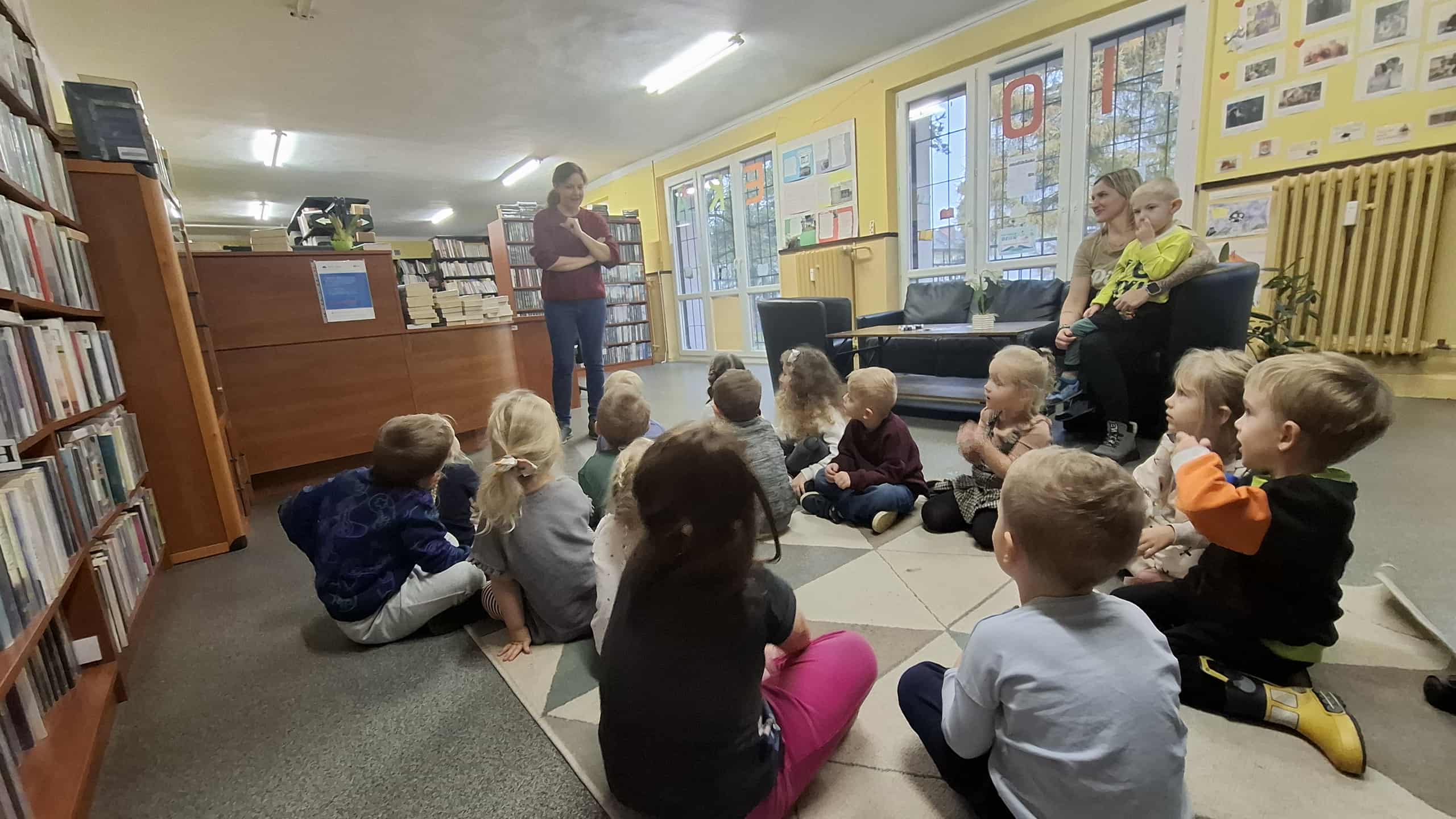 Bibliotekarka oraz dzieci biorące udział w lekcji bibliotecznej