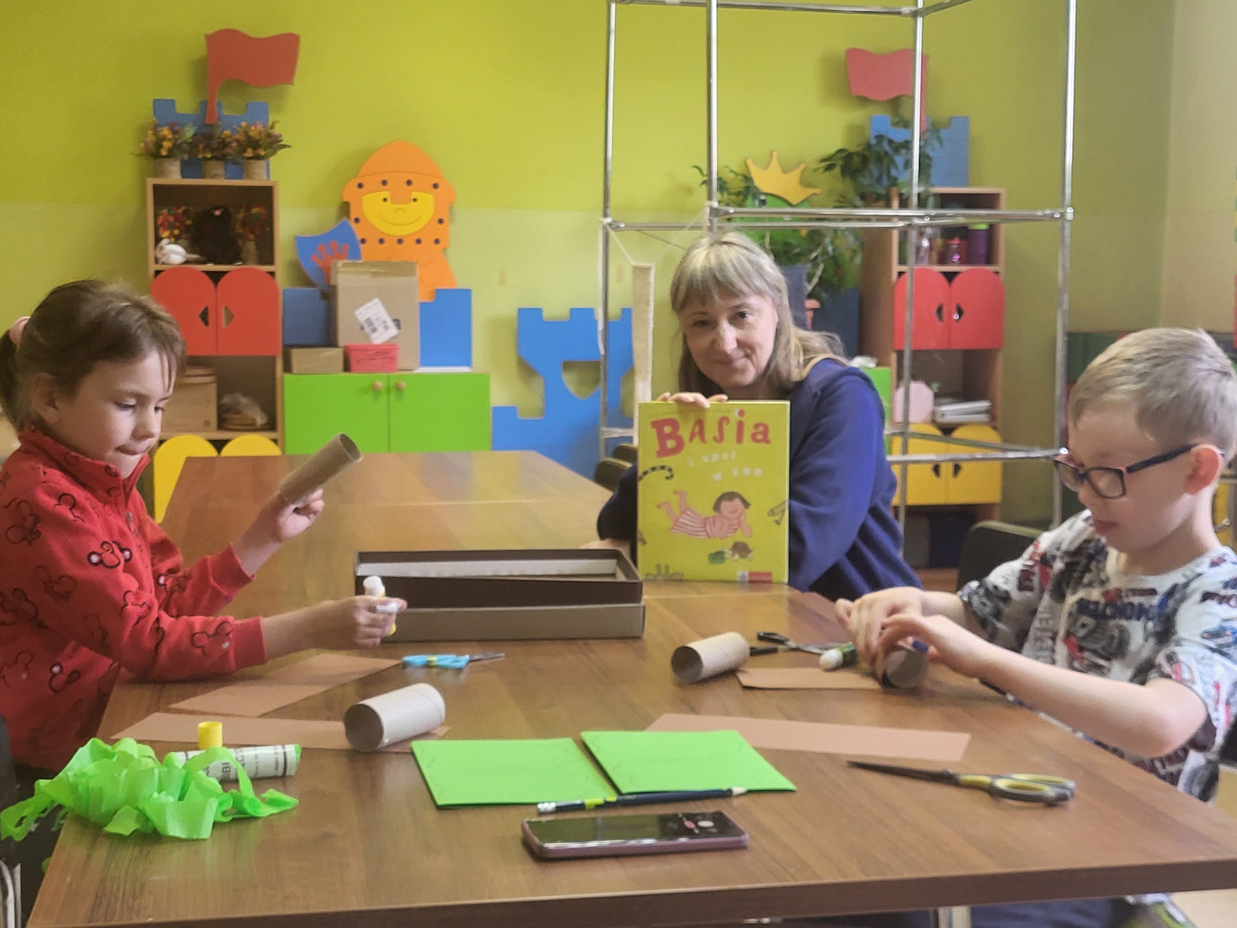 Bibliotekarka oraz dzieci biorące udział w lekcji bibliotecznej