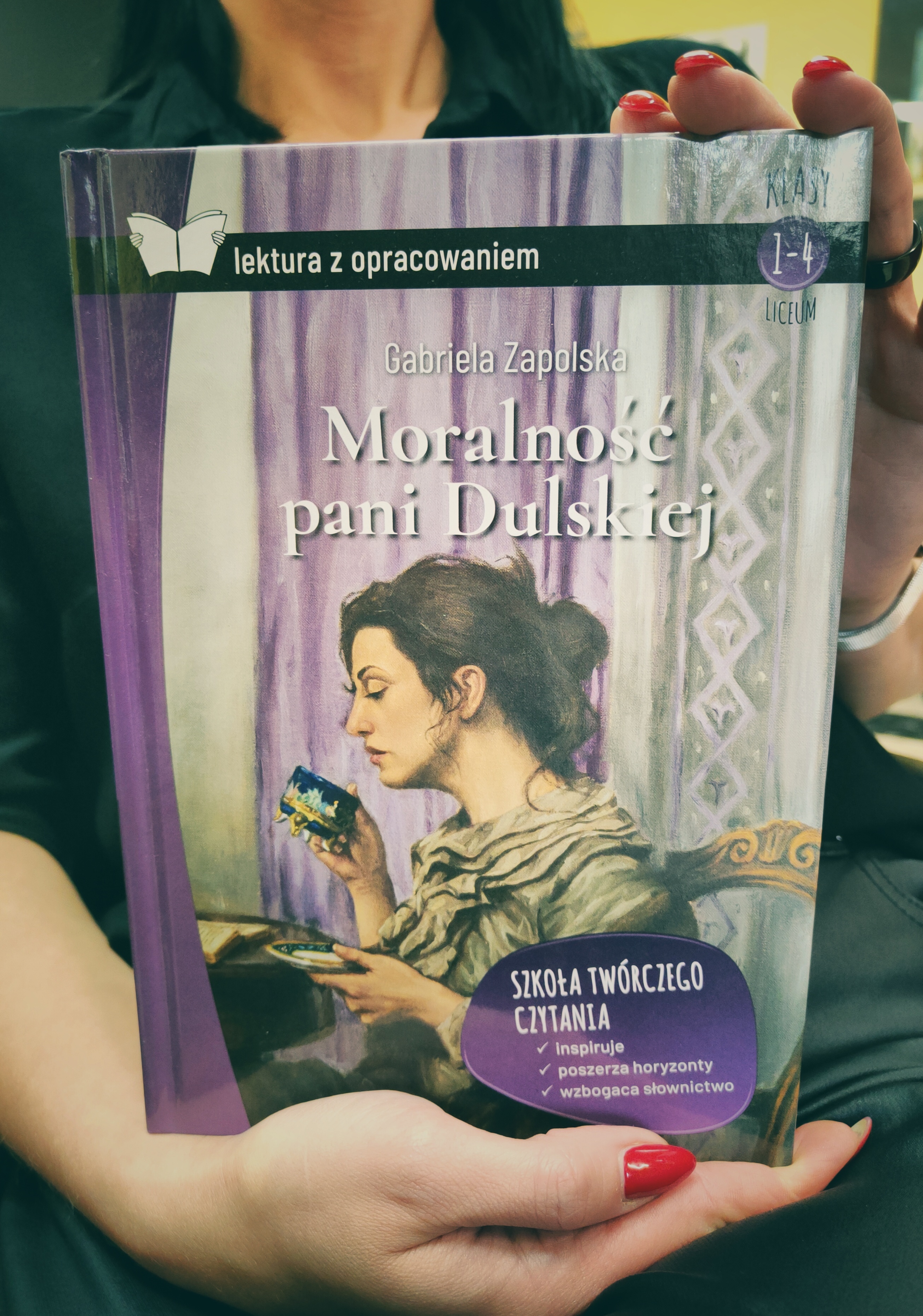 Książka okładką do przodu trzymana w rękach